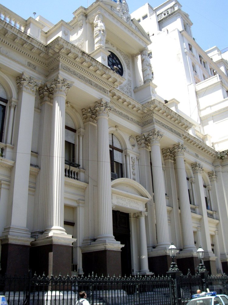 Fachada blanca de estilo renacentista del Banco Central, con columnas corintias, esculturas y un reloj en lo alto.