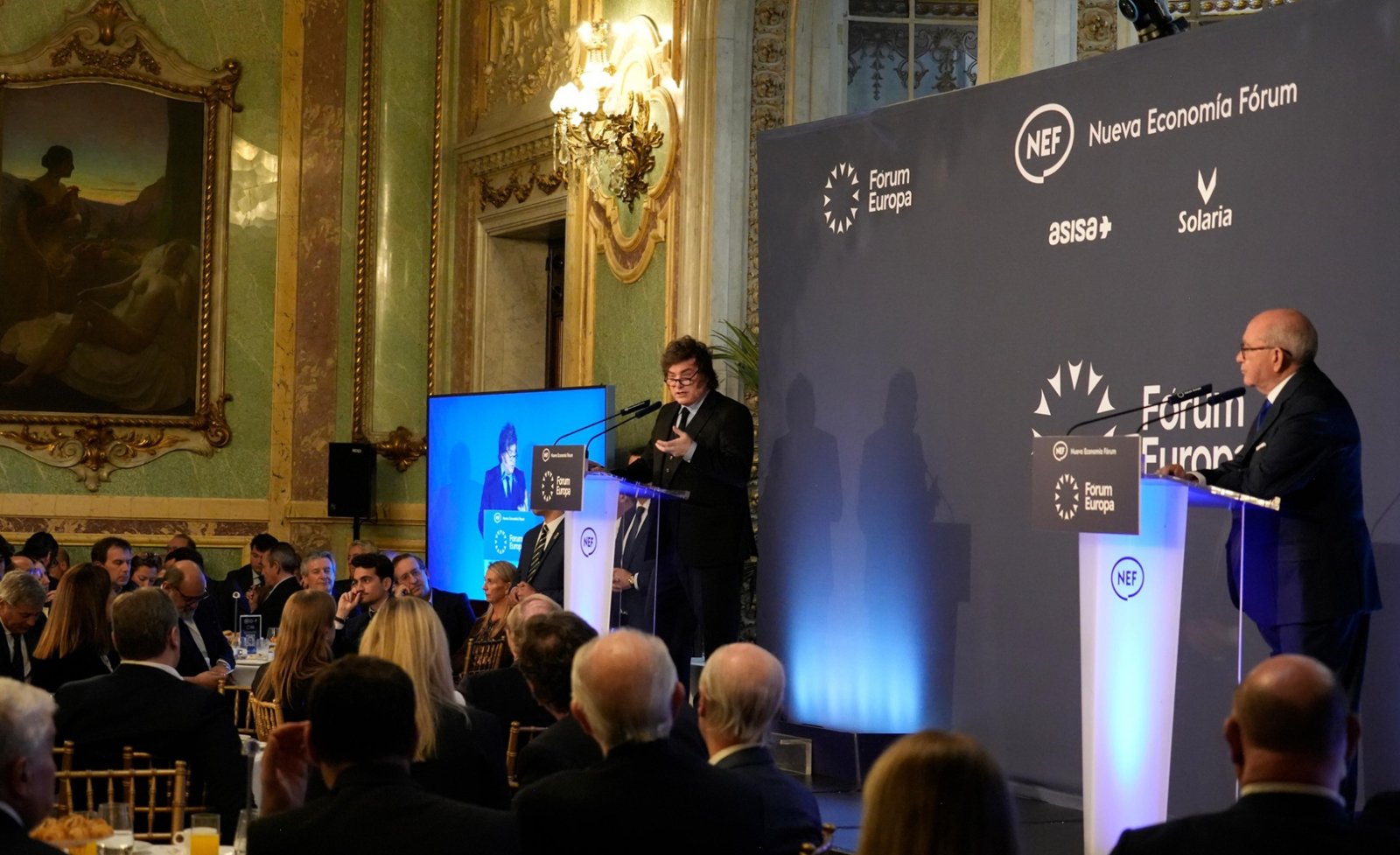Javier Milei habla desde un atril en el Fórum Europa, en un salón del Real Casino de Madrid, ante un público sentado a las mesas
