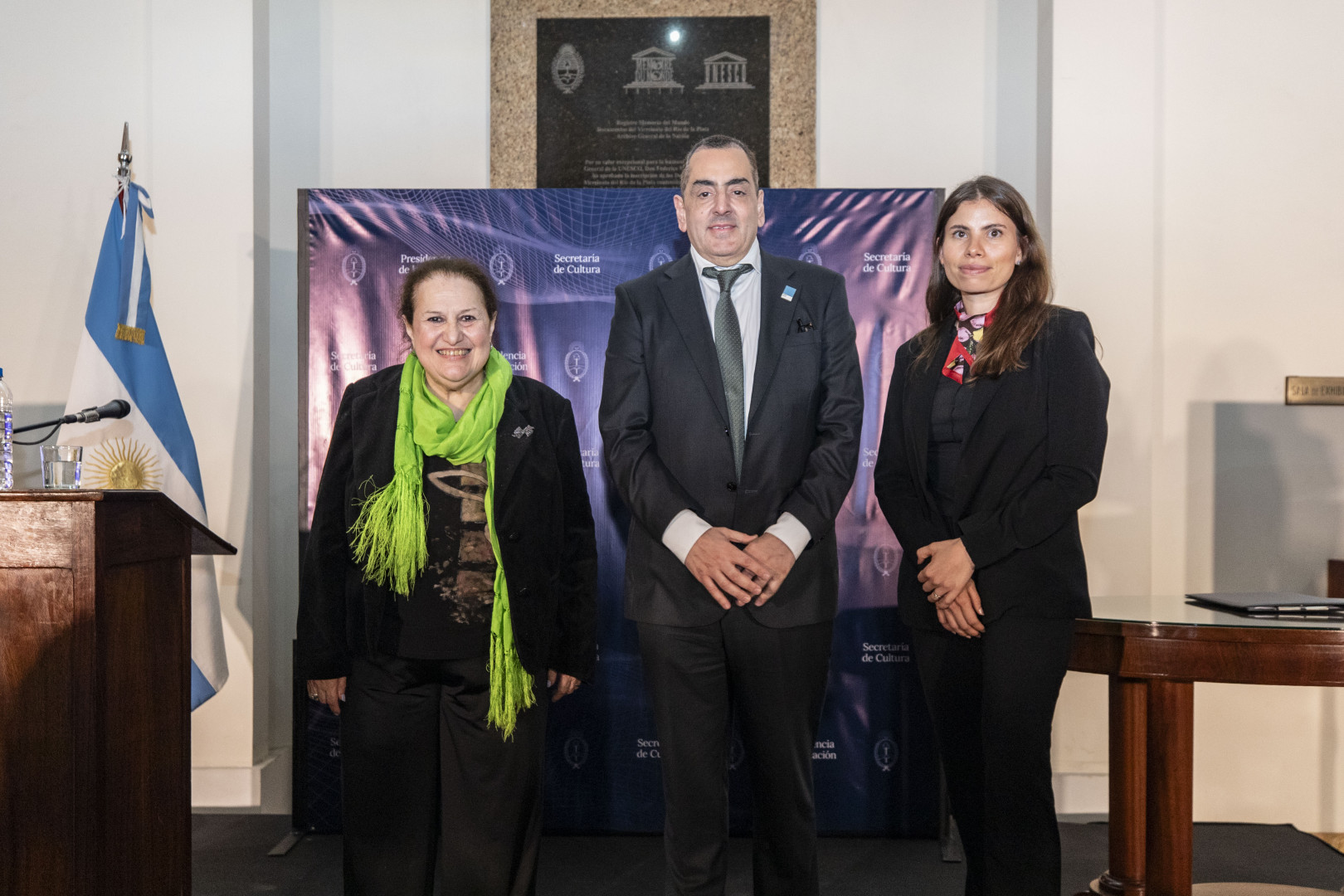 Liliana Barela, Leonardo Cifelli y Tania Yedro posan delante de un panel de la Secretaría de Cultura