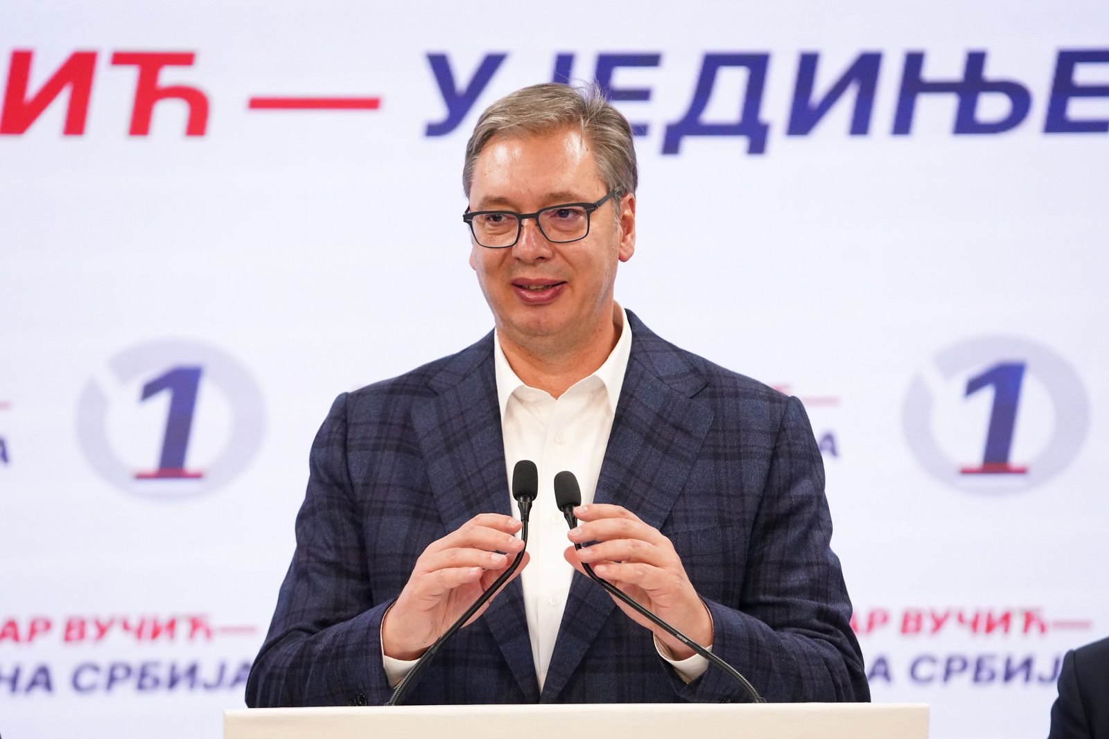 Aleksandar Vučić habla en un atril frente a un panel con el nombre de su lista, Serbia Unida