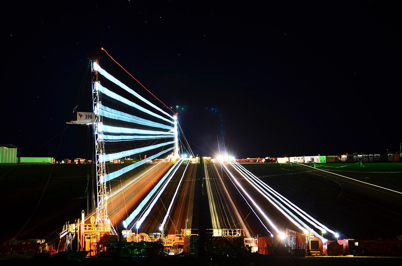 Torre de perforación iluminada de noche, con estelas de luz de una toma de larga exposición, en un yacimiento de Vaca Muerta