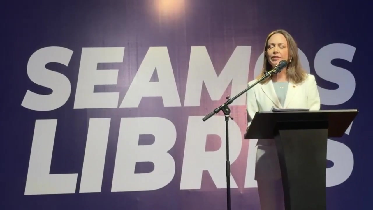 María Corina Machado habla en un atril frente a un cartel que dice «Seamos libres», en el Aula Magna de la UCAB