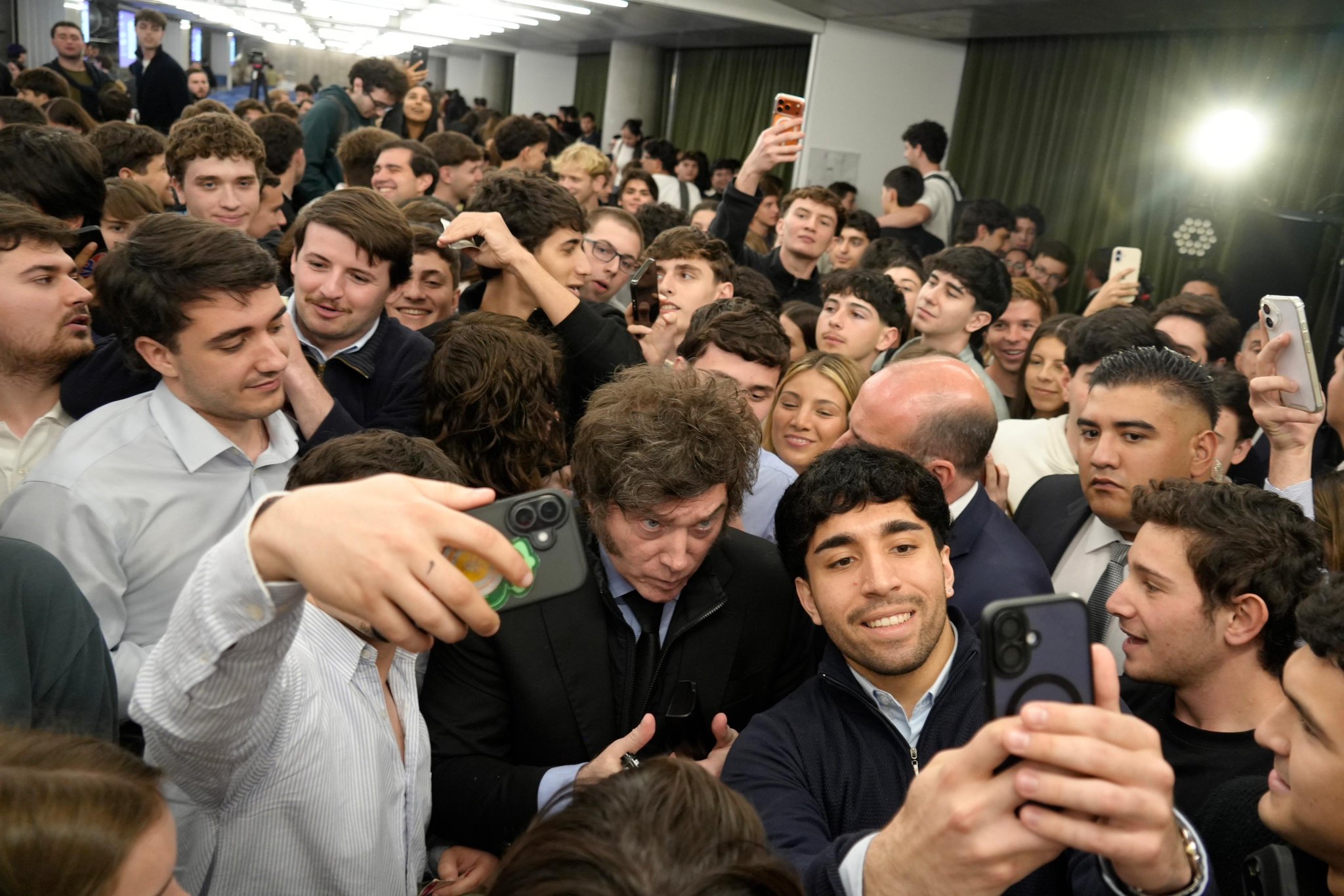 Javier Milei, rodeado de estudiantes que se sacan selfis con sus teléfonos, en un salón de la Universidad Torcuato Di Tella.